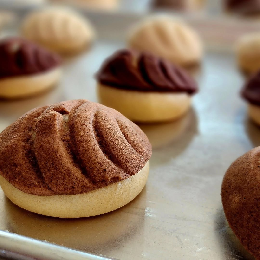 Closeup of chocolate conchas by La Concheria on a baking sheet